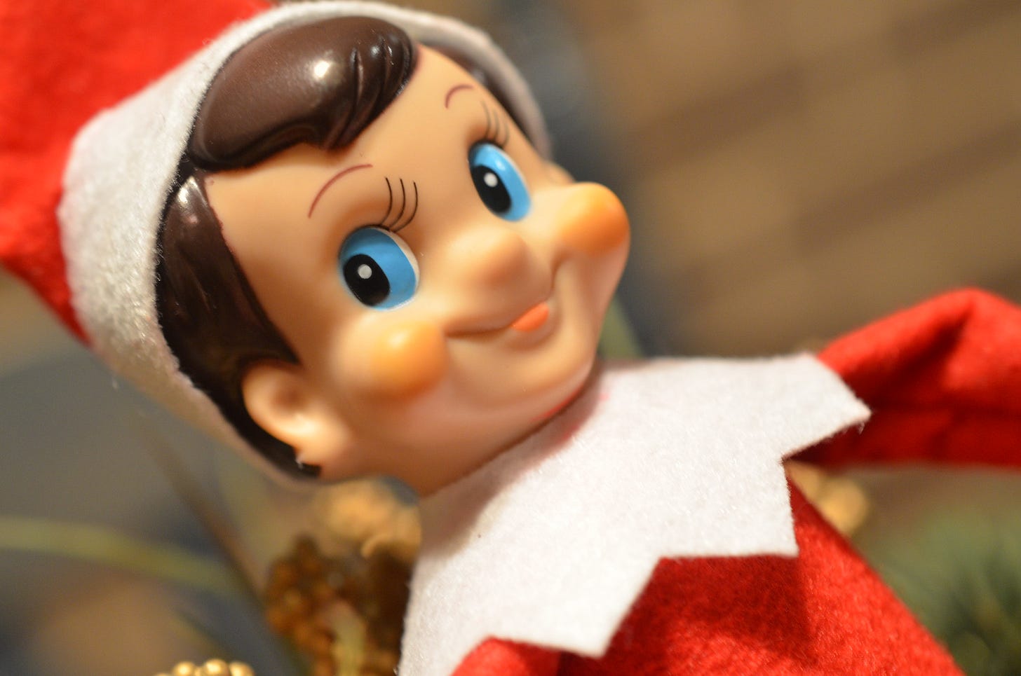 Close up photograph of an elf doll with a red and white hat and suit, blue eyes, and brown hair.