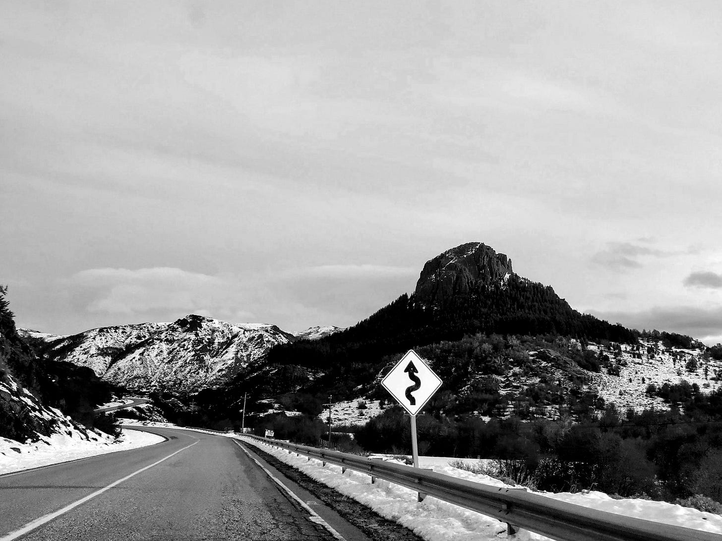 a road with a sign on it and mountains in the back a road with a sign on it and mountains in the back