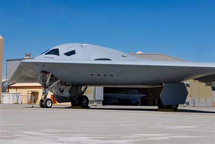 Photo 1: A U.S. Air Force stealth bomber taxis on a rain-slicked runway at night, representing the precision strike capabilities deployed during the initial phase of Operation Epic Fury. Photo 2: A U.S. Navy guided-missile destroyer patrols the hazy blue waters of the Strait of Hormuz, maintaining a presence near the critical global oil chokepoint. Photo 3: U.S. Army paratroopers in full combat gear board a military transport aircraft during a rapid-response deployment to the Middle East in March 2026. Photo 4: An aerial view shows a commercial oil tanker being escorted by a U.S. Navy littoral combat ship through the volatile waters of the Persian Gulf. Photo 5: Technicians in clean-room suits inspect rows of precision-guided missile components on a high-tech automated assembly line in an American defense plant.