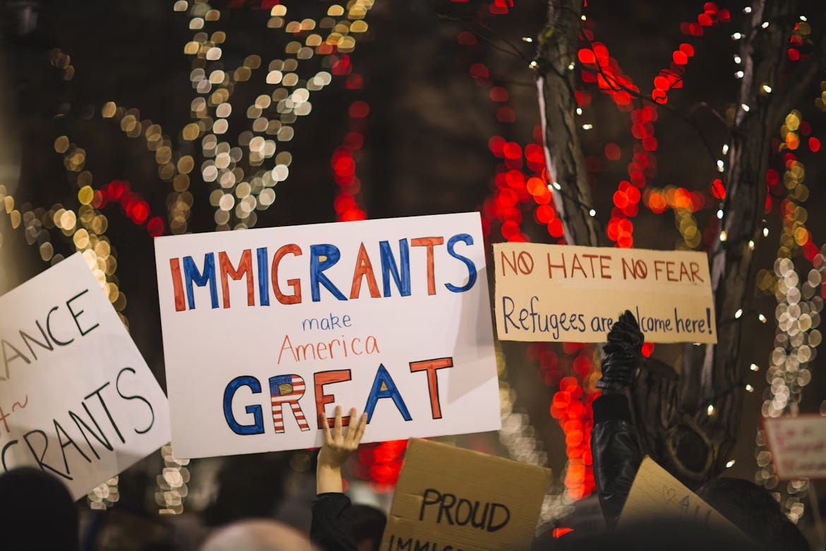 A photo of pro-immigrant signs held up at a protest. One sign reads "Immigrants make America Great." Another sign says "No Hate No Fear, Refugees are Welcome Here!"