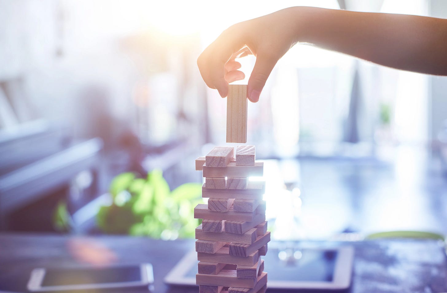 Game of Jenga with another piece being added which might collapse and become the tipping point