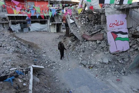 A Palestinian walks past graffiti and the rubble of buildings, ahead of the holy fasting month of Ramadan, amid a ceasefire between Israel and Hamas, in Khan Younis, in the southern Gaza Strip, February 27, 2025.
