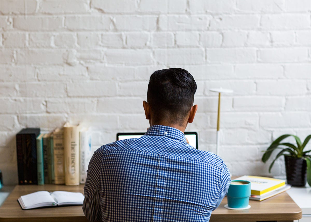 Pic of the back of a man sat at a desk while working from home.