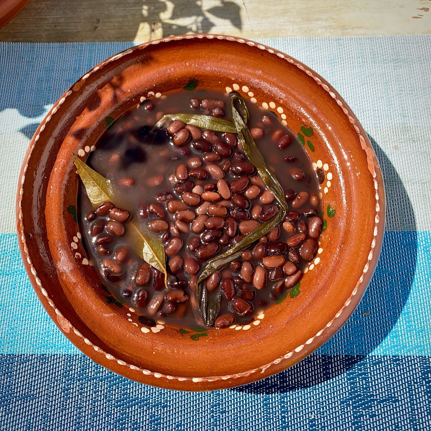 Frijoles de olla made with black beans, avocado leaves, epazote, and cebolla cambray.