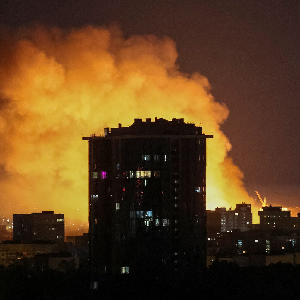 An explosion lights up a sky behind a building.