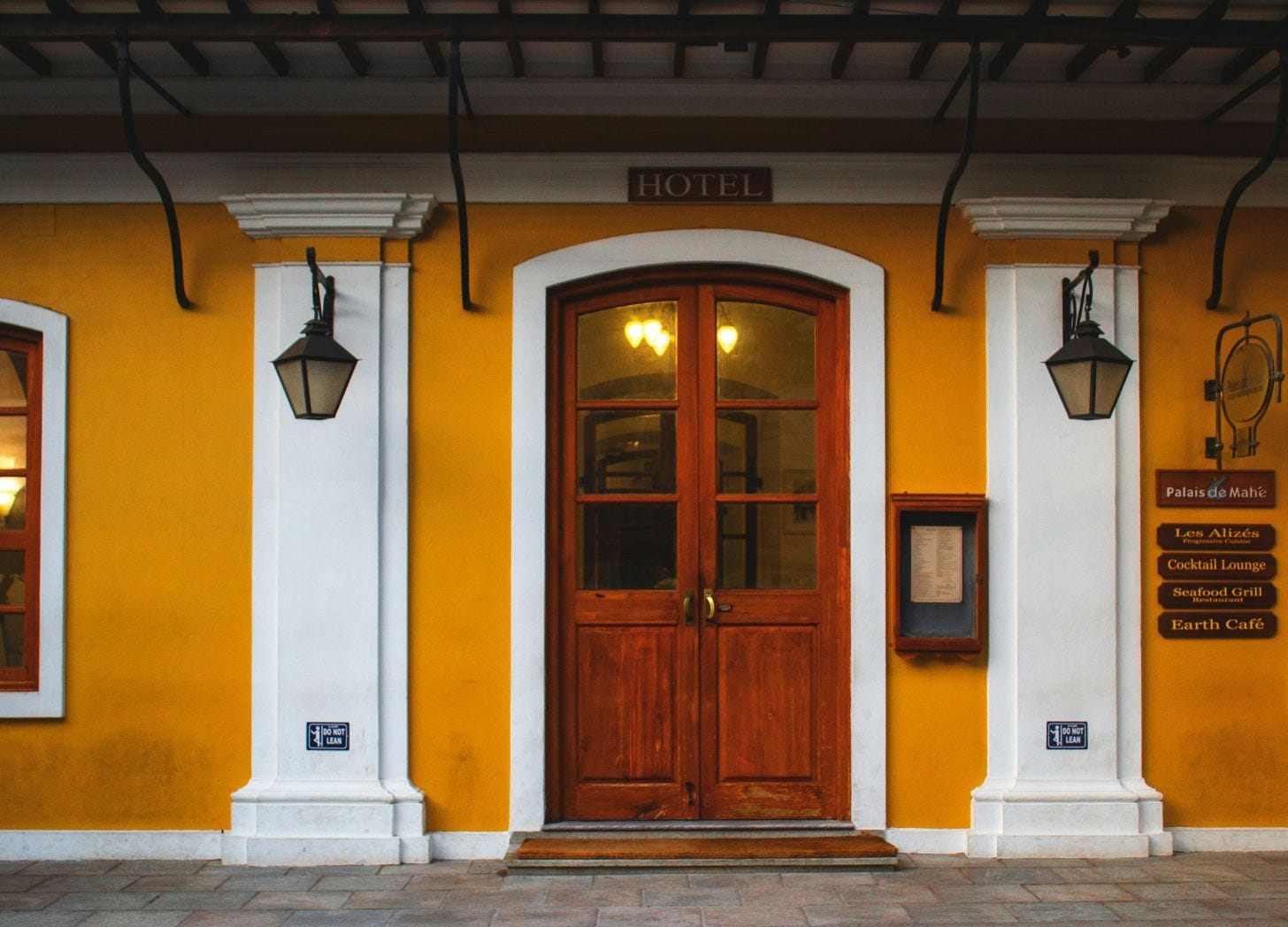 Warmly lit boutique hotel entrance with wooden doors and simple signage, showing a clean and welcoming first impression for guests. Warmly lit boutique hotel entrance with wooden doors and simple signage, showing a clean and welcoming first impression for guests.