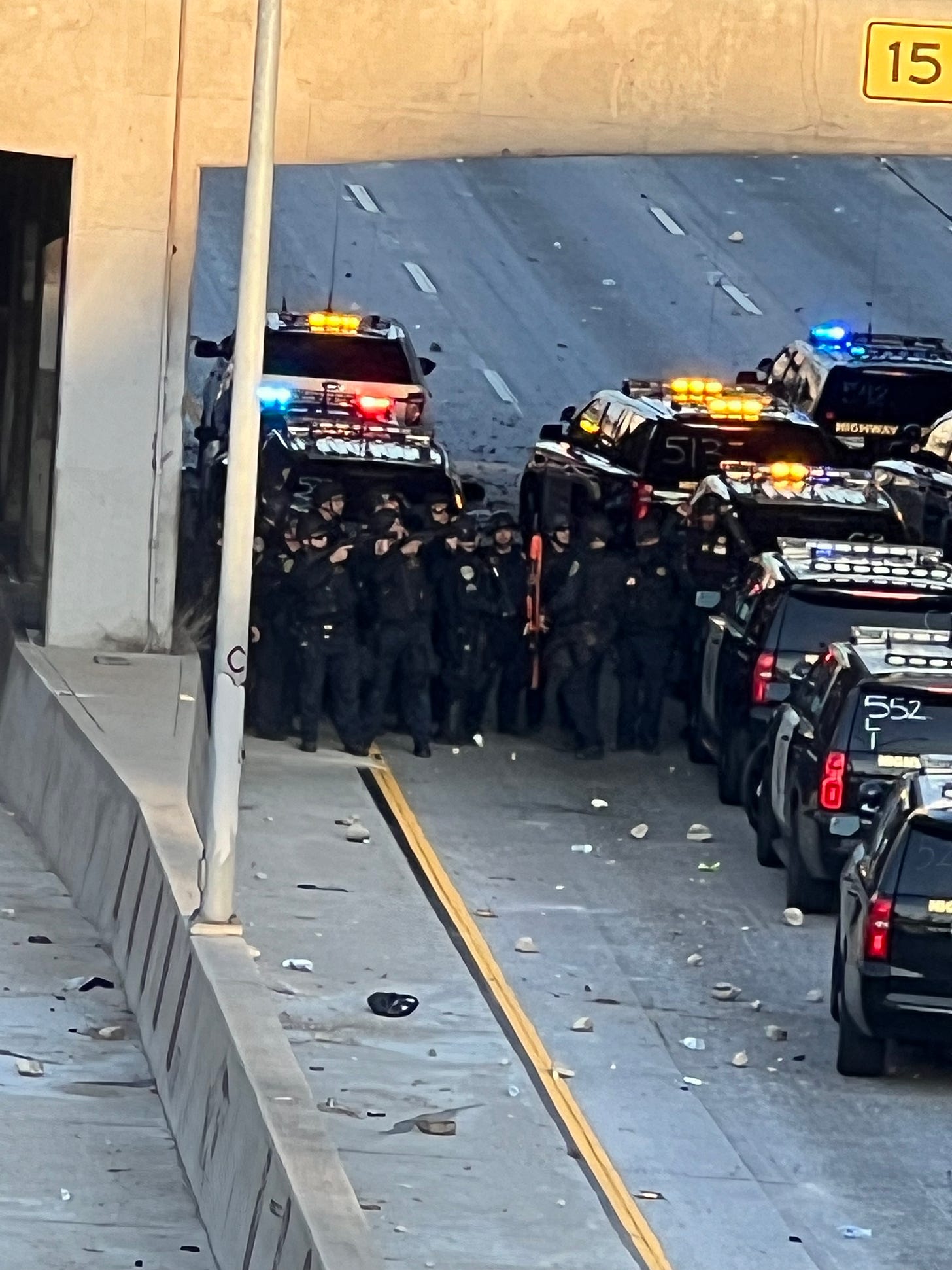 Police huddle next to vehicles in underpass as rocks are thrown at them by protesters.