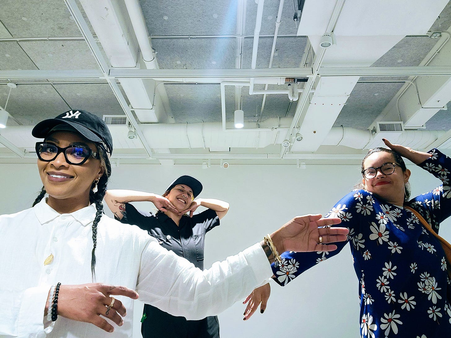 Three smiling people posing in the fore, mid and background in an open gallery.