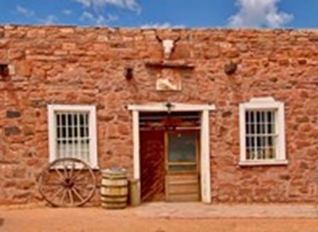 A brick building with a wagon wheel with Hubbell Trading Post National Historic Site in the background

AI-generated content may be incorrect.