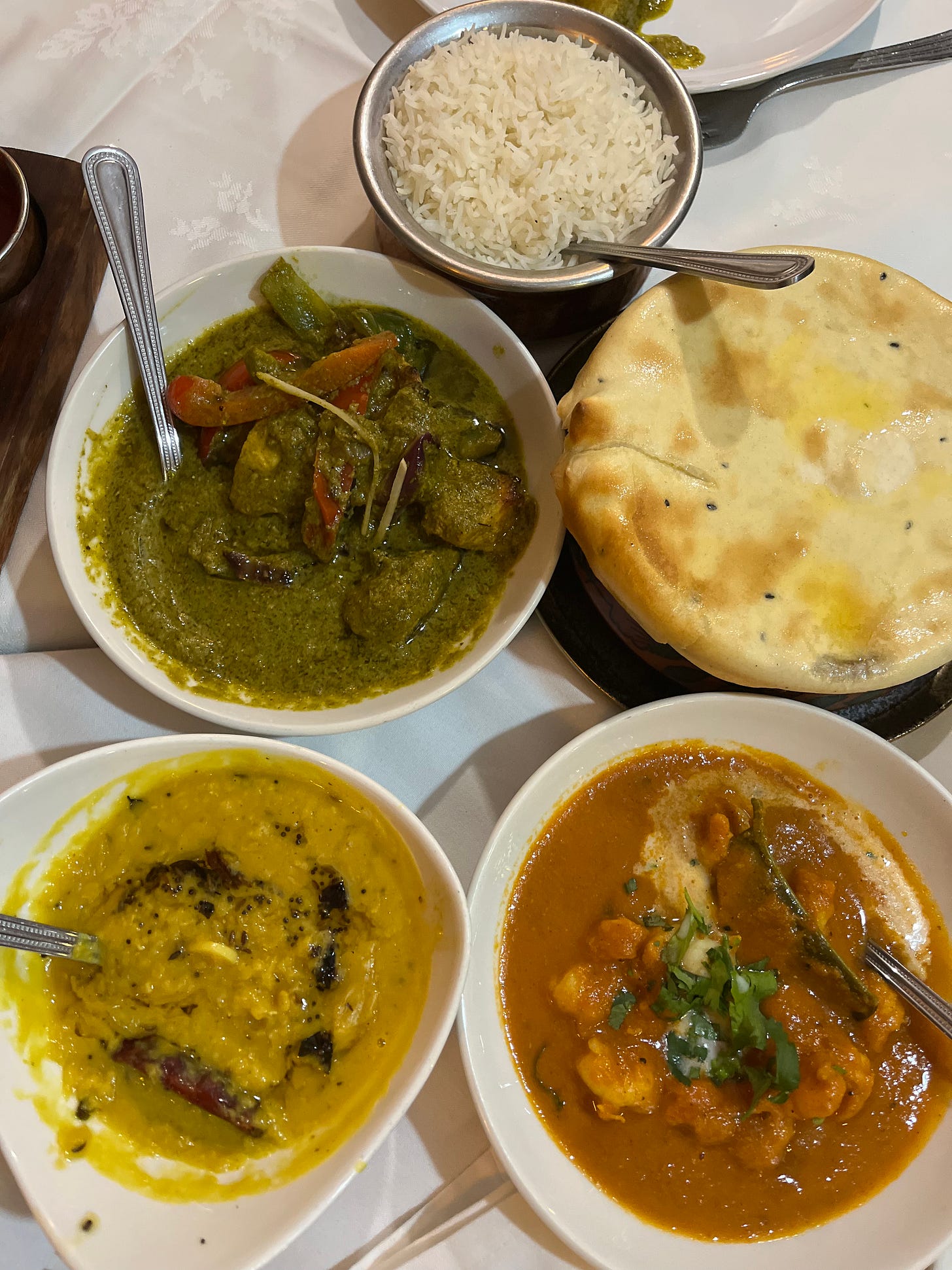 table set with food: naan, coriander chicken curry, naan, lamb, rice, prawns, dhal table set with food: naan, coriander chicken curry, naan, lamb, rice, prawns, dhal