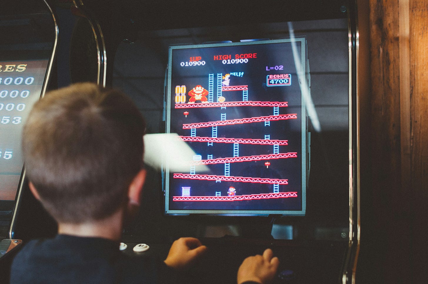 photo of a kid playing the video game Donkey Kong on a stand-up arcade machine photo of a kid playing the video game Donkey Kong on a stand-up arcade machine