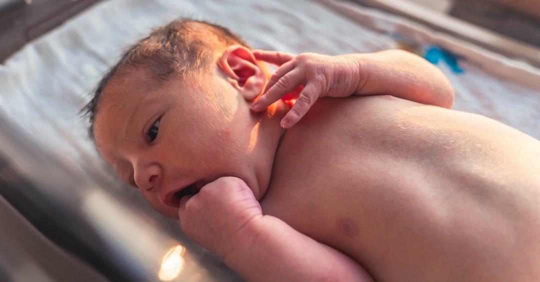topless baby lying on blue textile
