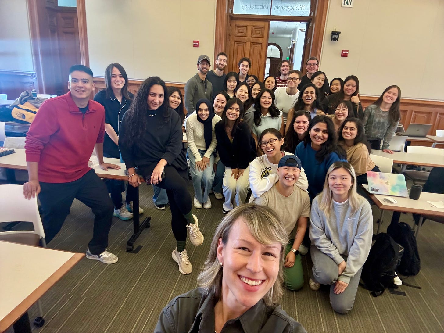 Group selfie with a UC Berkeley class, students gathered together in a wood-paneled classroom, smiling toward the camera.
