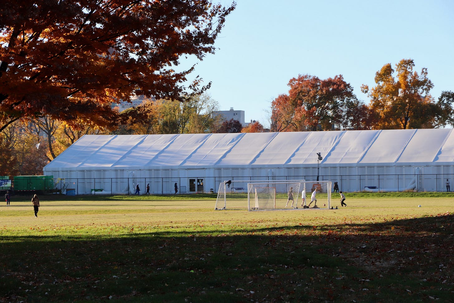 A massive tent is shown on an athletic field with soccer players in the foreground.