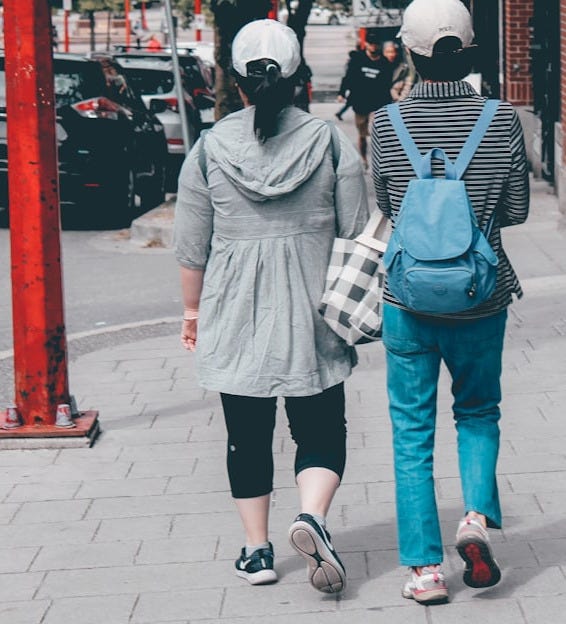 2 person wearing mask standing on sidewalk during daytime