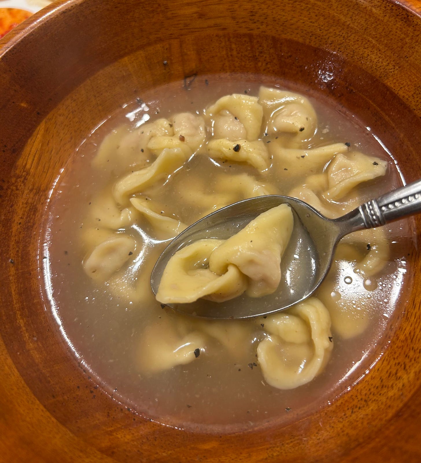 Tortellini in broth. Each tortellini is connected, like a chain, to another.
