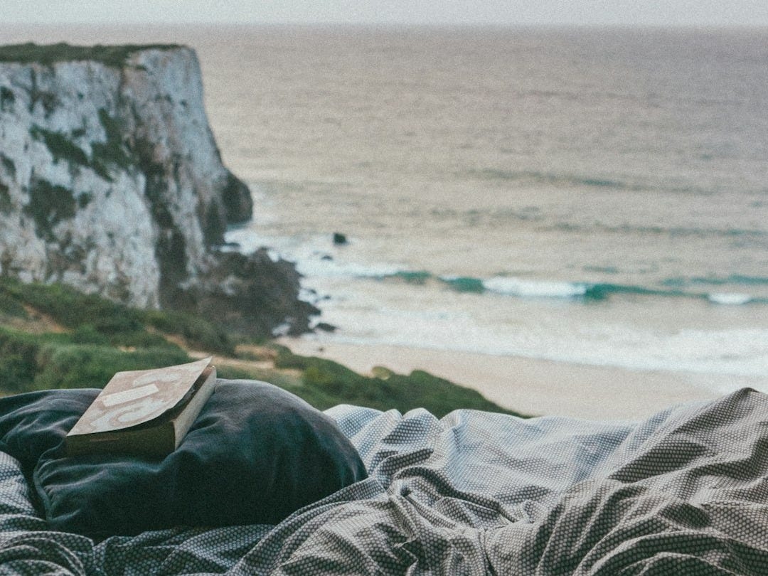 book on gray pillow on bed near seat during daytime