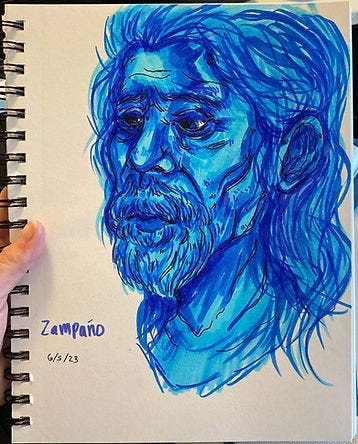 Blue sketch of a bearded man with long hair, expressing a somber mood. Text reads “Zampaño 6/5/23” on left of beige sketchbook. Blue sketch of a bearded man with long hair, expressing a somber mood. Text reads “Zampaño 6/5/23” on left of beige sketchbook.