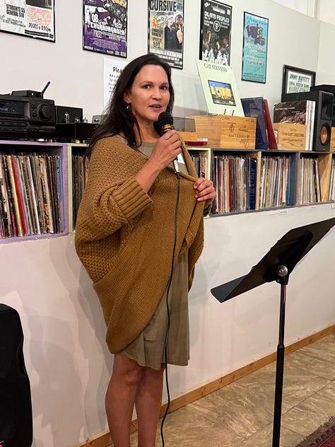 A group of people reading at an open mic inside a small wine bar.