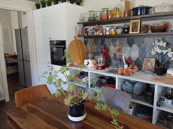 Kitchen with wooden table and armchairs in the centre of the room.