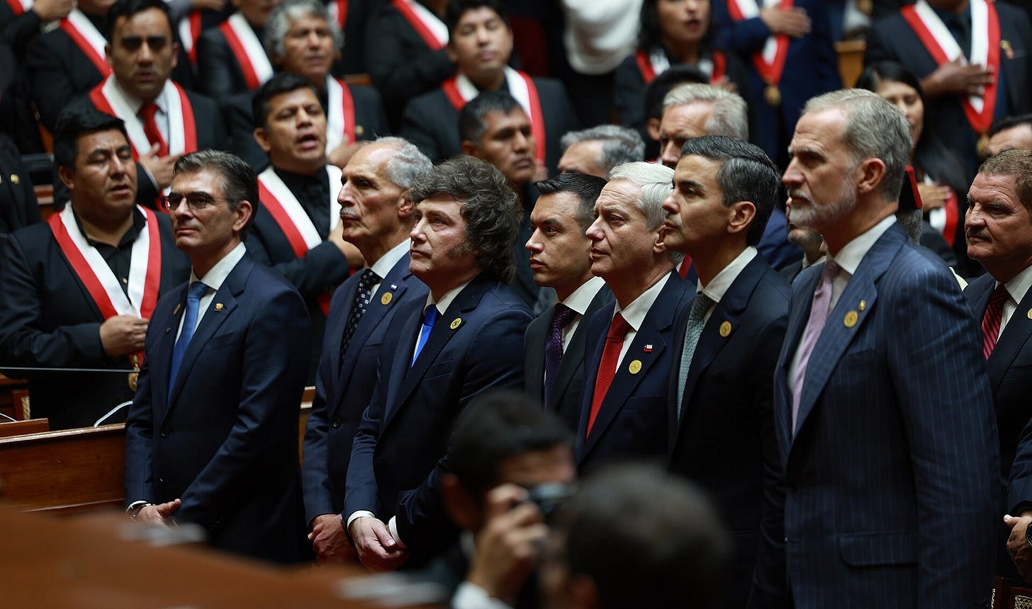 A row of foreign heads of state in dark suits, including Argentina's Javier Milei, stands among Peruvian legislators wearing red-and-white presidential sashes in the chamber of Peru's Congress. A row of foreign heads of state in dark suits, including Argentina's Javier Milei, stands among Peruvian legislators wearing red-and-white presidential sashes in the chamber of Peru's Congress.