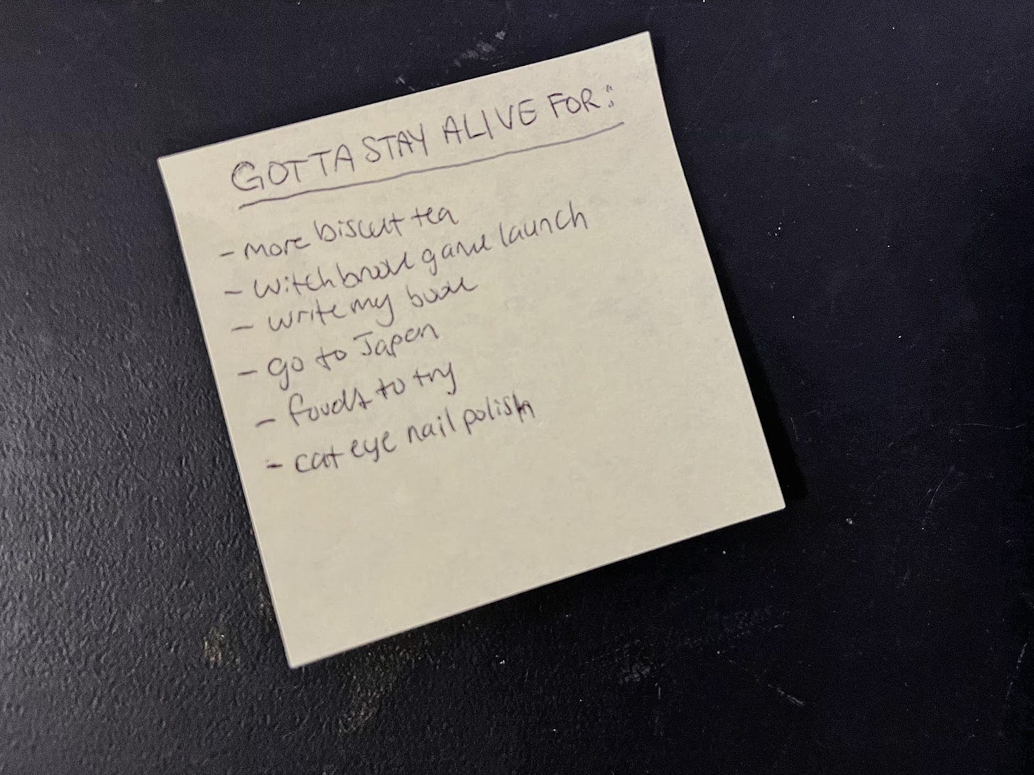 A post it note with reasons to stay alive: more biscut tea, Witchbrook game launch, write my book, go to Japan, foods to try, cat eye nail polish