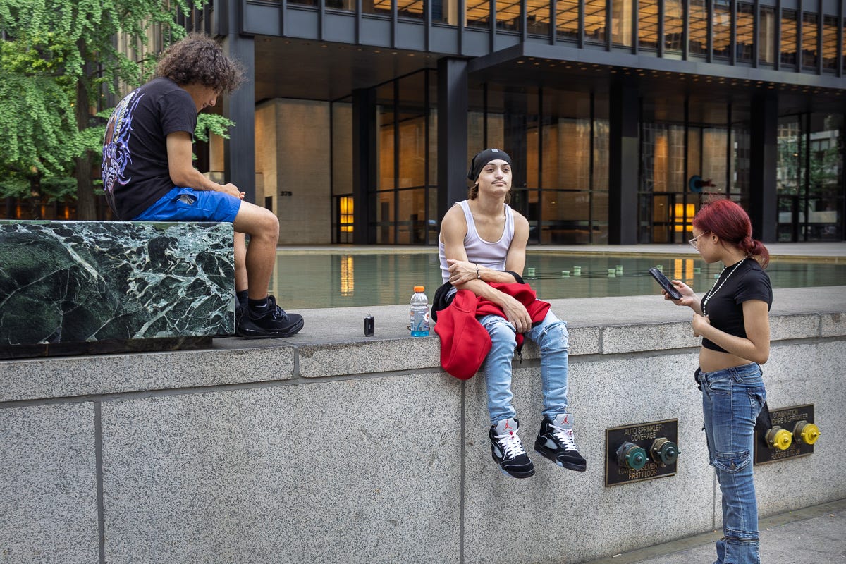 Three young people sitting and standing near a fountain on Park Avenue in New York City Three young people sitting and standing near a fountain on Park Avenue in New York City