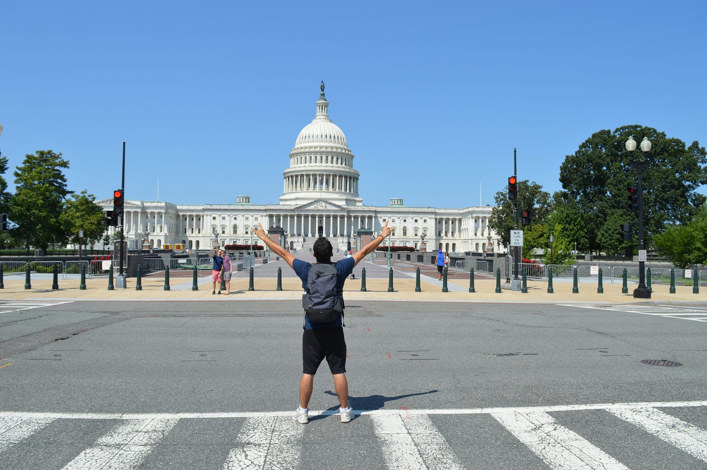 Person with arms raised, facing the U.S. Capitol building