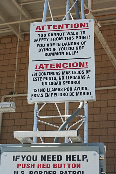 Sign reding "Attention: you cannot walk to safety from this point! You are in danger of dying if you do not summon help!" in English and Spanish on a rescue beacon along the border in Arizona. 