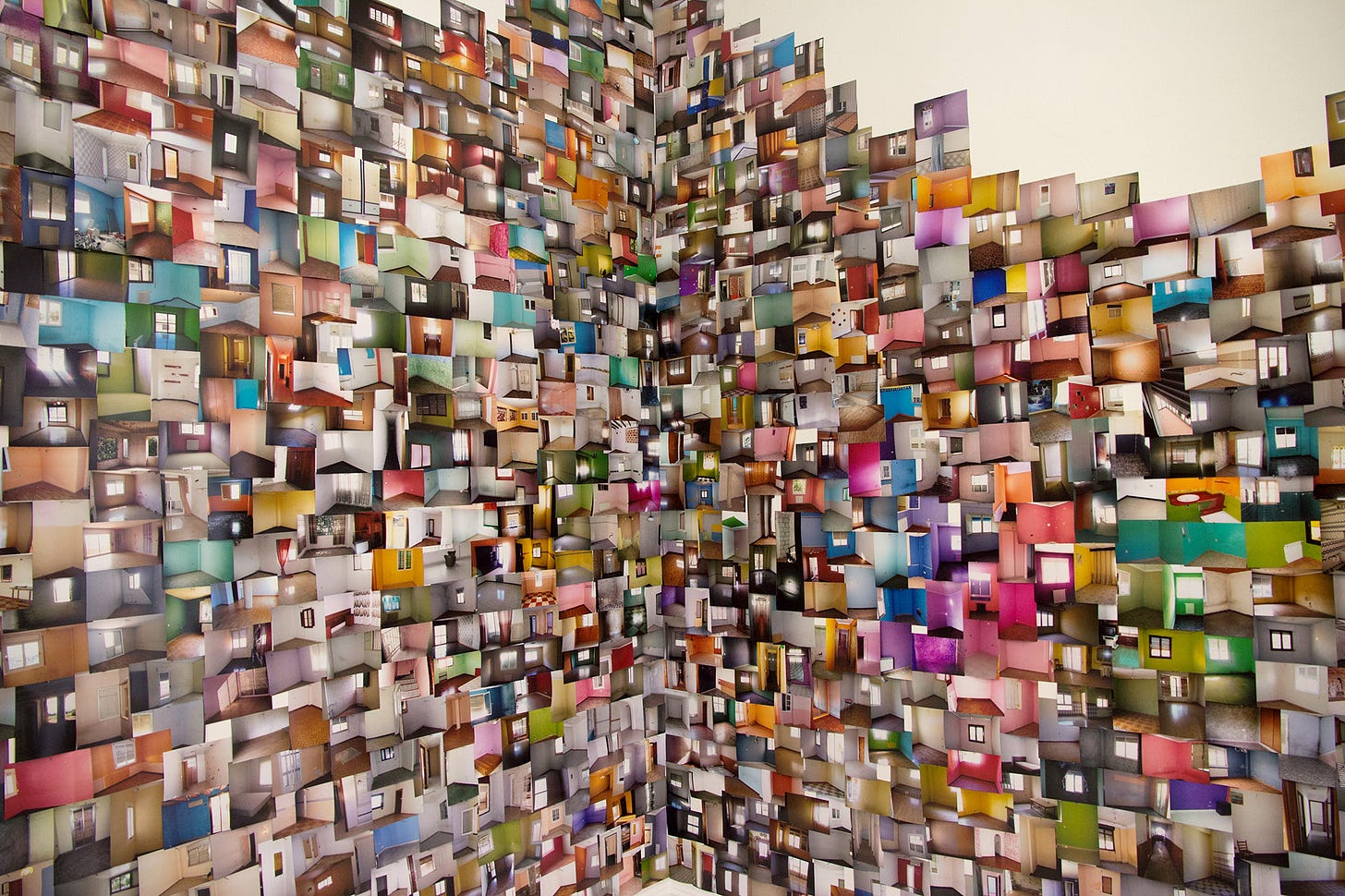 Due pareti ricoperte di foto di appartamenti vuoti, di ogni foggia, dimensione e colore. È un opera del fotografo spagnolo Iván Pérez, si intitola Interior Europeo.