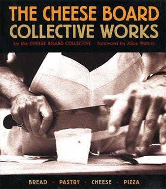 Image of the cover of a cookbook, titled "The Cheese Board Collective Works", by the Cheese Board Collective. Image underneath title is focused on a person's hands, cutting a piece of cheese with a large knife. Image of the cover of a cookbook, titled "The Cheese Board Collective Works", by the Cheese Board Collective. Image underneath title is focused on a person's hands, cutting a piece of cheese with a large knife.