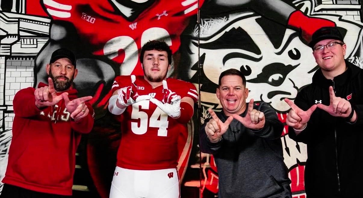 Brady Bekkenhuis stands alongside Wisconsin coaches Casey Rabach, AJ Blazek, and Jared Thompson during his official recruiting visit to Madison.