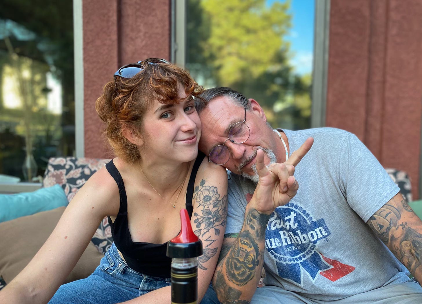 Smiling young woman sitting close to older man who rests his head on her shoulder with eyes closed
