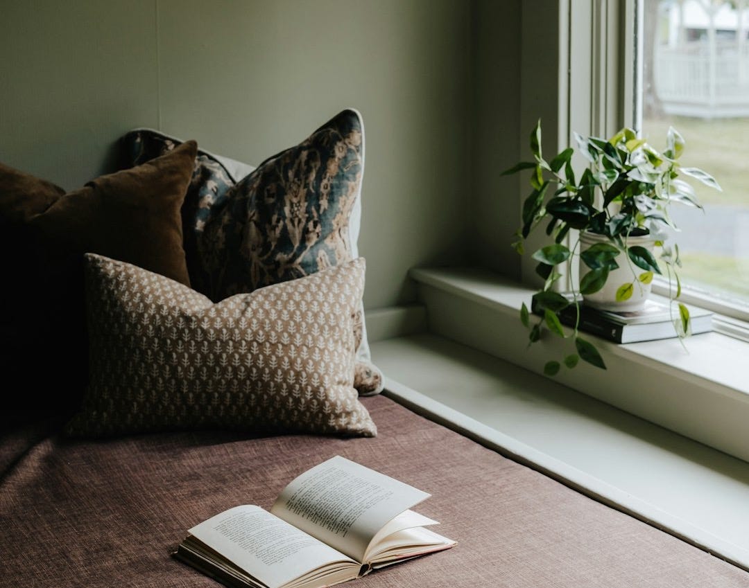 A bed with a book on top of it next to a window