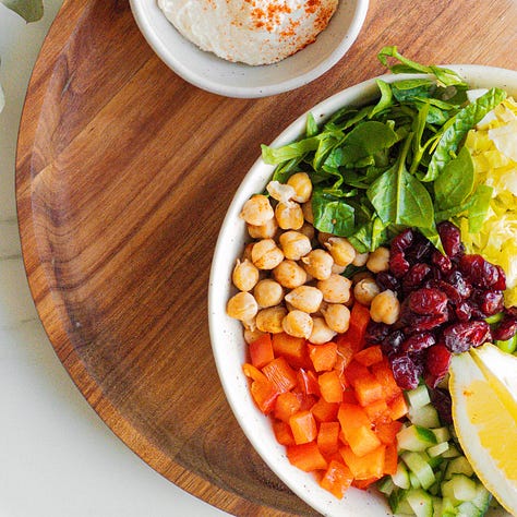 Chickpea-Edamame Salad served in a bowl with fresh spinach, romaine, cucumber, bell pepper, and a creamy hummus dressing.