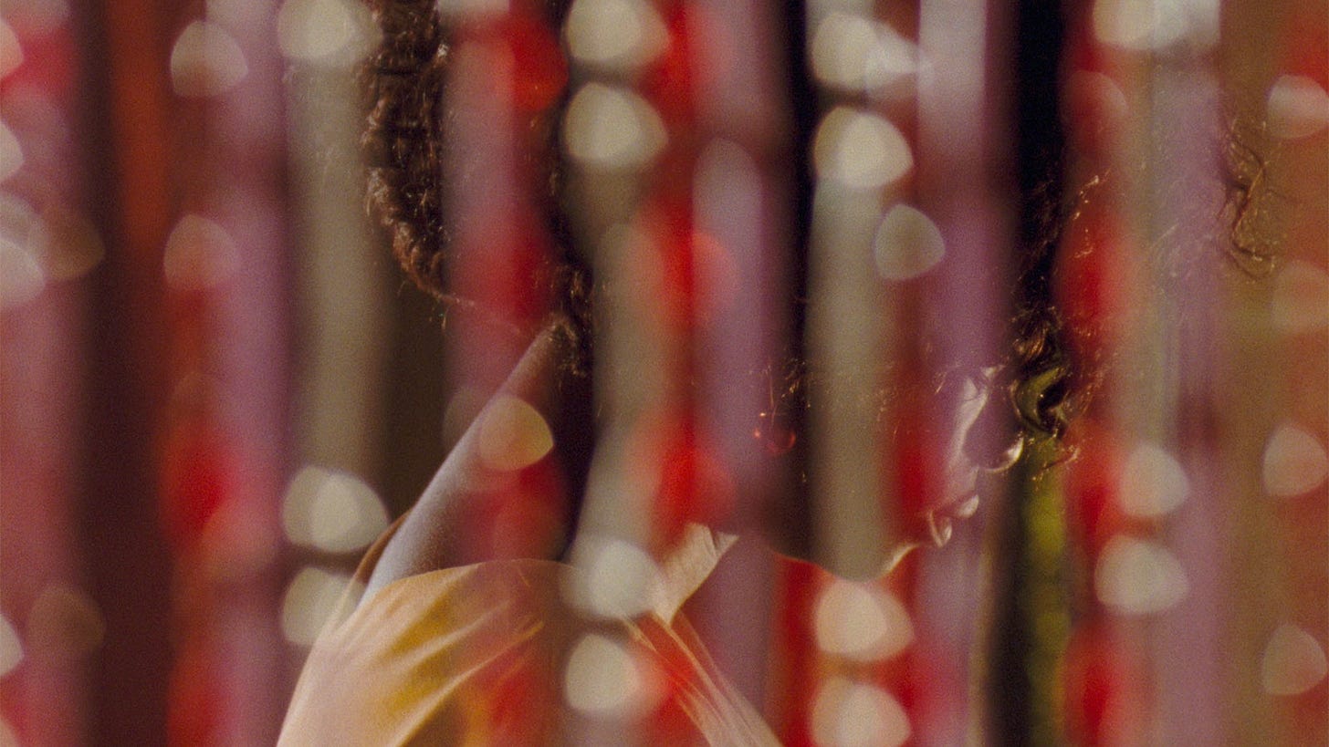 Still from “Eyimofe” showing a woman behind a curtain
