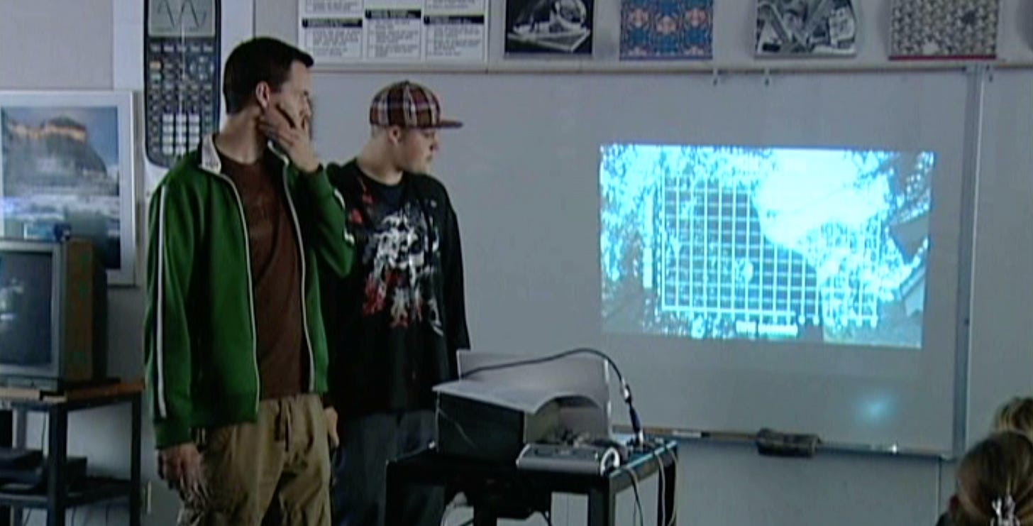 Me, teaching in front ofa projector with a kid watching a video, deep in thought.