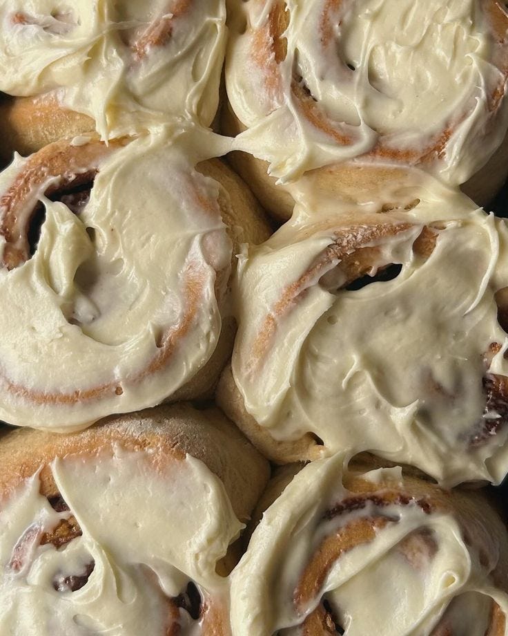 This may contain: there are many cinnamon rolls with icing on them