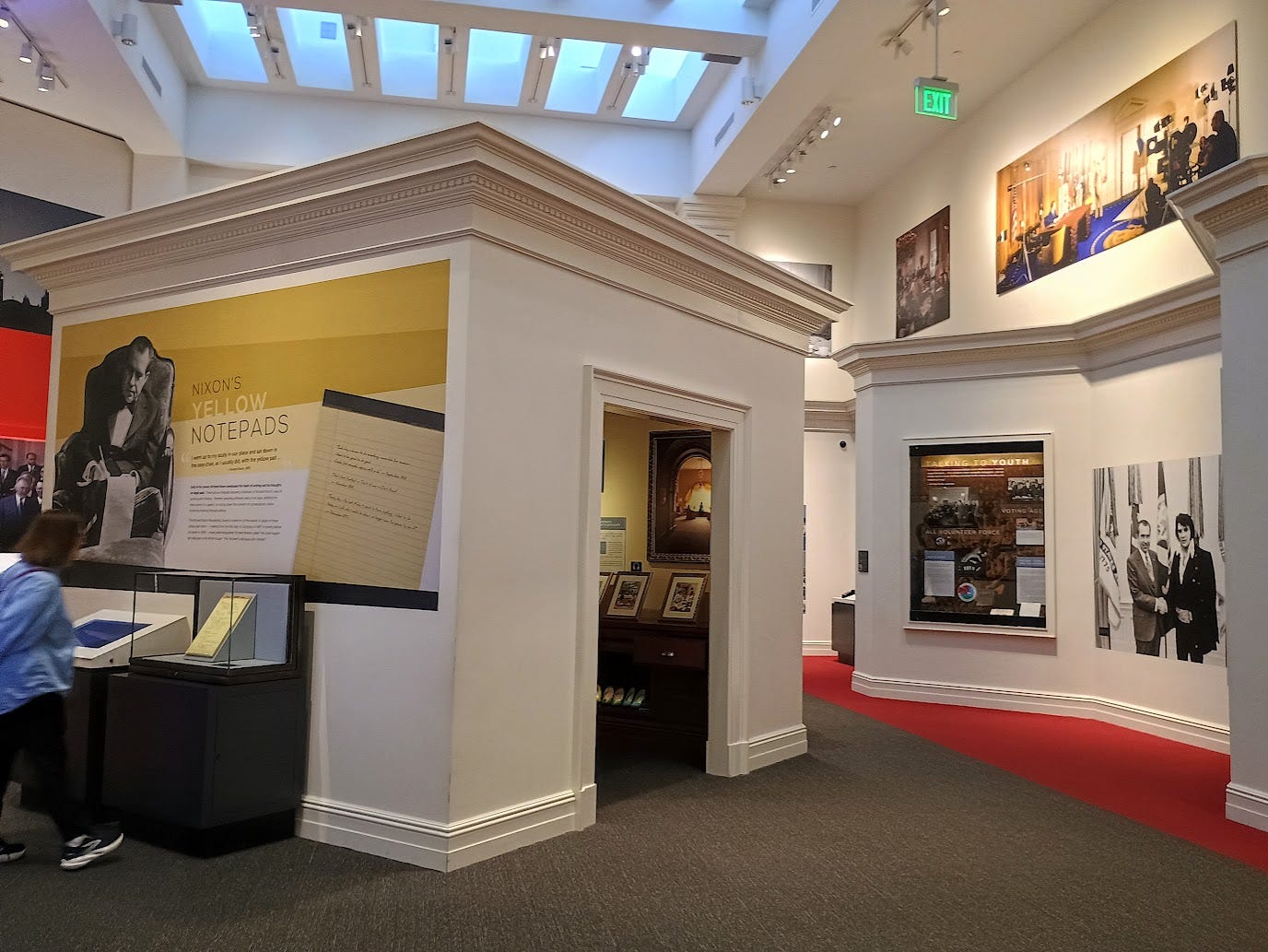 Large open exhibit area, including a small hut placed awkwardly in the center, with exhibit on Nixon's Notepads on the outside. Photo of Nixon and Elvis Presley visible on walls