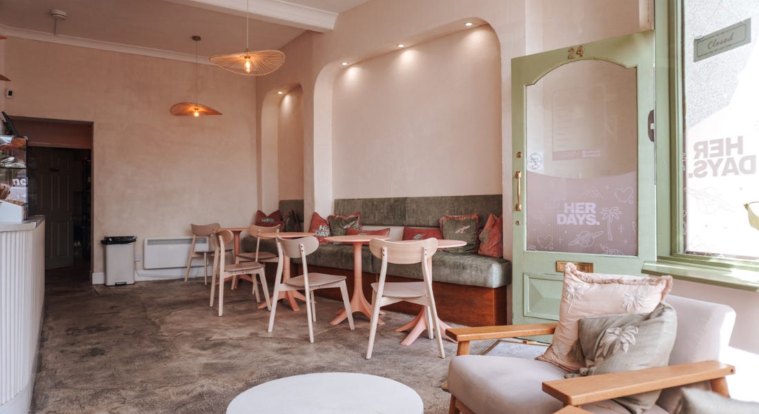 A restaurant interior with green and pink furniture, washed walls, and a green door A restaurant interior with green and pink furniture, washed walls, and a green door