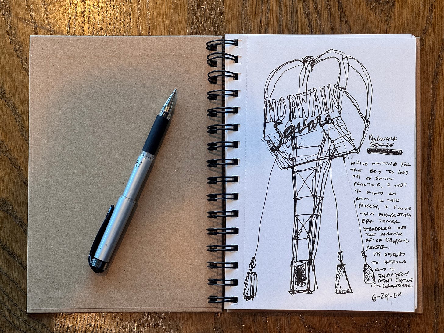 a sketchbook open to the first page with an urban sketch of a large tower sign with the words Norwalk Square written on all four sides. 