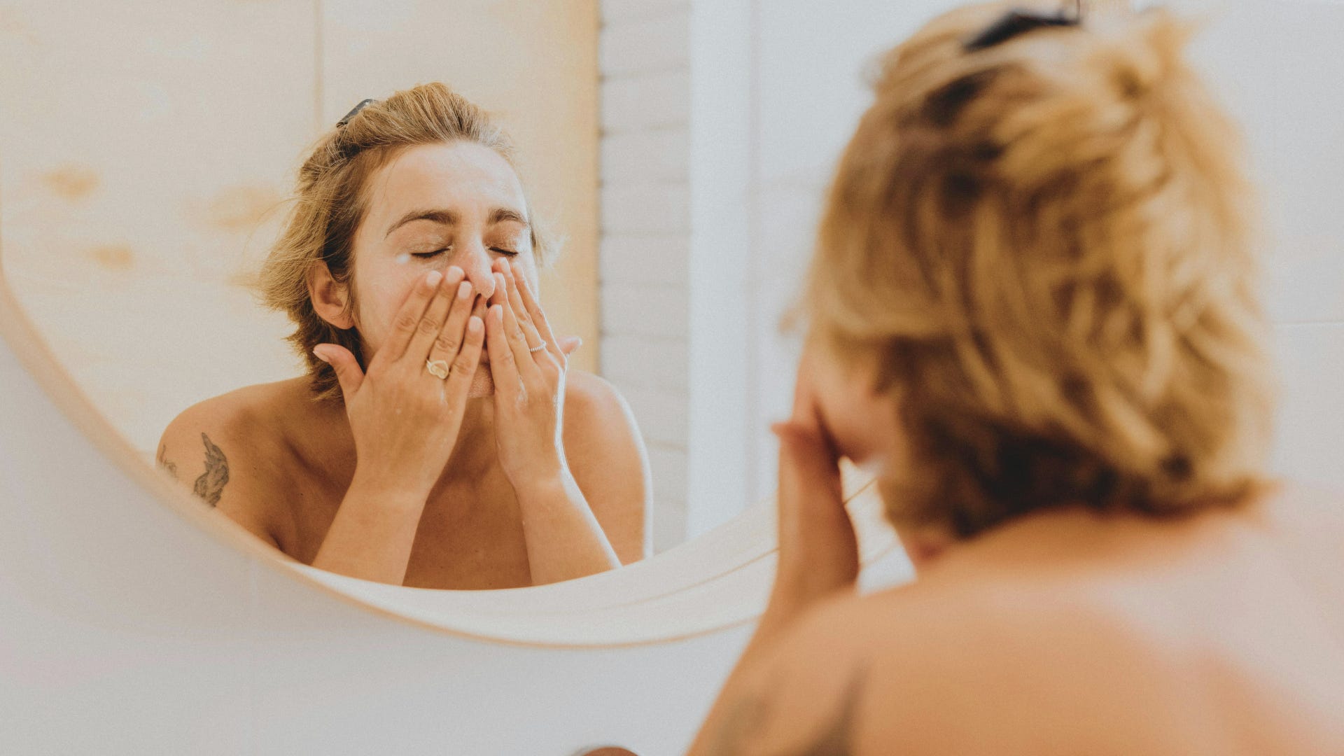 young woman washing her face in the mirror