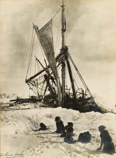 Frank Hurley captures a group of dogs watching the Endurance shortly before she sinks to the bottom of the Weddell Sea, November 1915.