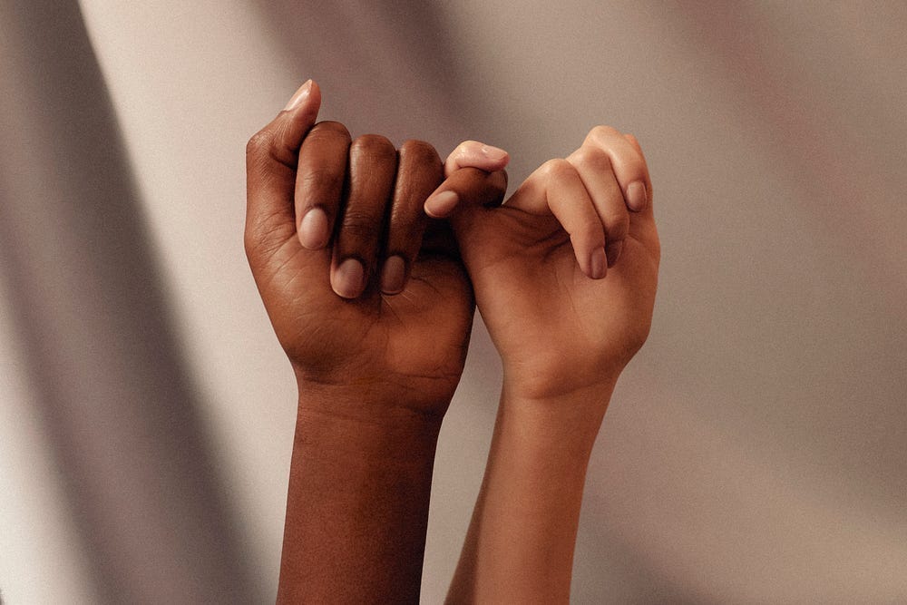 Two hands holding each other by their pinky finger Two hands holding each other by their pinky finger