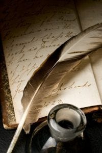 feather and ink pot on writing paper