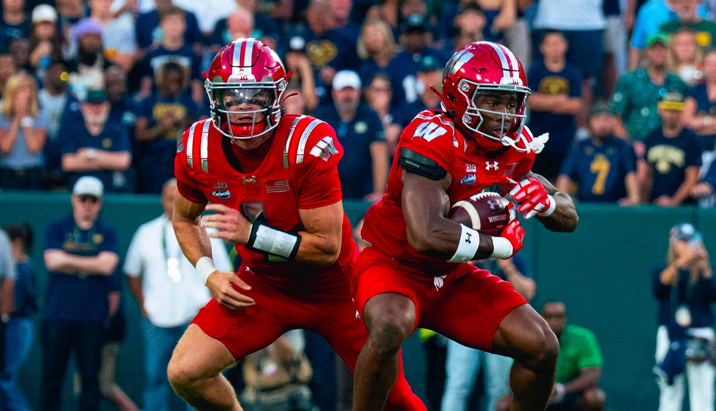 Wisconsin Badgers quarterback Colton Joseph hands the ball off to running back Abu Sama.