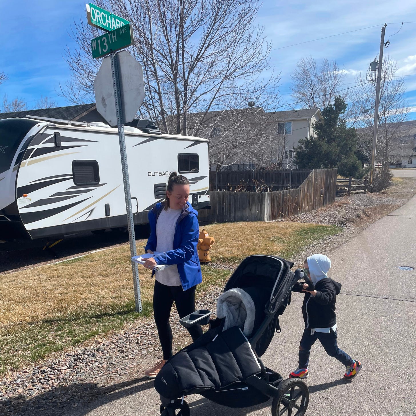 a woman holding a stack of paper looks over her shoulder at her five year old pushing his stroller along a road a woman holding a stack of paper looks over her shoulder at her five year old pushing his stroller along a road