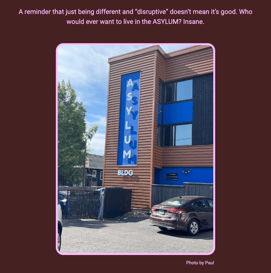 The image shows a building with a vertical sign that spells out 'ASYLUM' in large blue letters against the side of the structure. The text above the image comments on the name of the building. Here is the alt text including all of the text that appears in the image:

"A photo of a multi-story building with wood siding, featuring a large vertical blue banner with the word 'ASYLUM' written in white capital letters. The building has blue window frames that match the banner, and there is a small sign that says 'BLDG' at the bottom of the banner. In the foreground, there is a partial view of a parking area with a car. Above the image, the text reads: 'A reminder that just being different and “disruptive” doesn’t mean it’s good. Who would ever want to live in the ASYLUM? Insane.' The image is outlined with a pink border and credited with 'Photo by Paul' at the bottom right corner."
