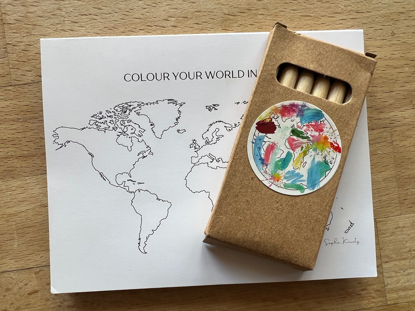 A close-up of the back of Sophie Krantz’s “Colour Your World” card, listing the six colour categories (Orange, Blue, Red, Yellow, Green, Black) that prompt reflection on markets, opportunities, visibility, partnerships, competitors, and knowledge gaps. A small QR code and Sophie’s signature are at the bottom of the card.