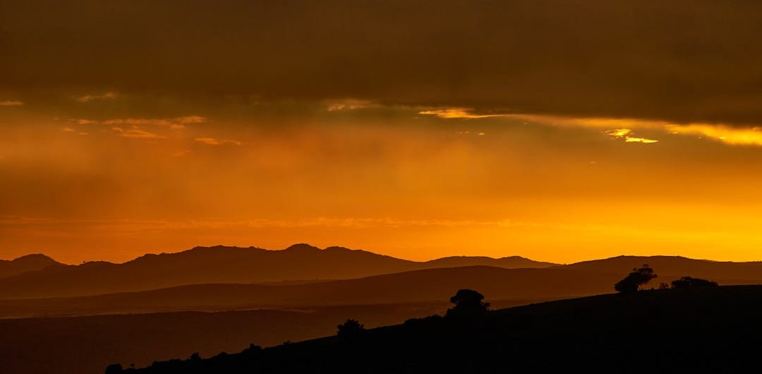 the sun is setting over the mountains in the distance